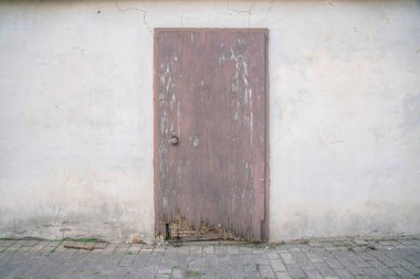 San Antonio, Teksas terk edilmiş bir binanın ahşap kapısı. Eski binanın dış tarafı boyanmış beton duvarla kaplı ve kapının üzerinde çatlak çizgiler var..