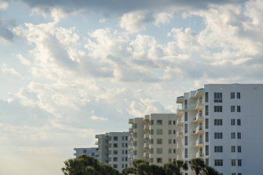 Destin, Florida 'da balkonlu apartmanların yan görüntüsü. Bulutlu gökyüzü arkaplanına karşı modern apartman dairesi sırası.