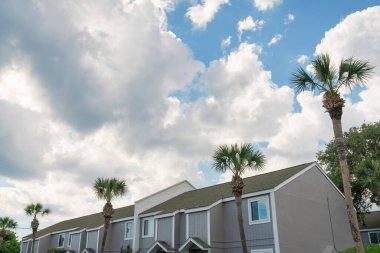 Gökyüzündeki kabarık bulutlara karşı bitişik evlerin alçak açılı görüntüsü... Destin, FL. Gri dış görünüşlü evler.