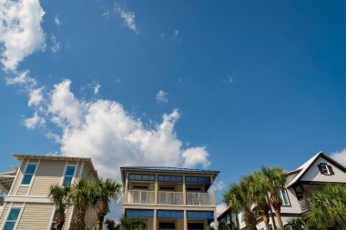 Destin, Florida 'da ahşap kaplamalı üç evin ön cephesi. Solda bej renkli bir ev, ortada balkonlu bir ev ve sağda kahverengi süslemeli bir ev var..