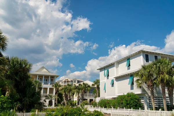 stock image Destin, Florida- Views of large residential houses with picket fence and palm trees. Neighborhood with wood sidings and balconies against the cloudy sky.