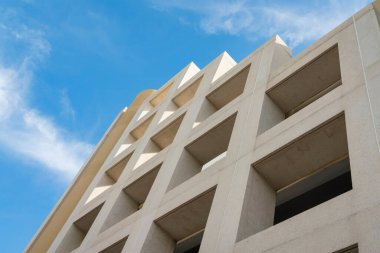 Miami, Florida 'da gökyüzünün altında kare pencereli açık bir binanın alçak açılı görüntüsü. Altından katmanlı çatı yapısı görünen bej renkli bir bina..