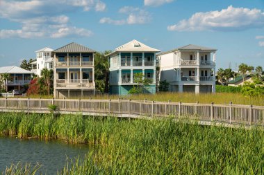 Destin, Florida- iskan bölgesinin göl kıyısında tahta korkuluklu tahta kaldırım. Üç katlı evlerin yakınındaki göldeki uzun otların üzerindeki patika..