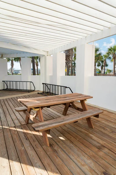 Destin, Florida- Wooden table with chairs near the open windows with views outdoor. Dining table on a wood planks flooring and painted white wall.