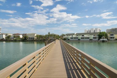 Destin, Florida 'daki yerleşim alanının yakınındaki bir gölün tuzlu sularının üzerinde sahil yürüyüşü. Gökyüzü arka planına karşı balkonlu evlere giden yol..