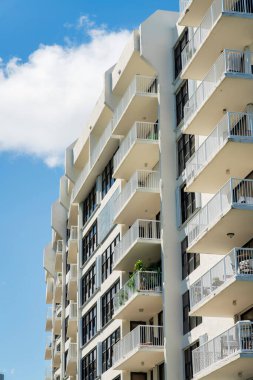 Miami, Florida 'da, balkonlu ve pencereli orta katlı bir apartman manzarası. Beyaz balkon parmaklıkları olan bir binanın dışında..