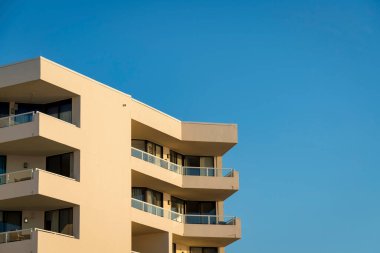 Destin, Florida 'da, mavi gökyüzüne karşı köşelerinde balkonları olan bir bina. Balkonlarda metal ve cam parmaklıklı bir binanın manzarası..