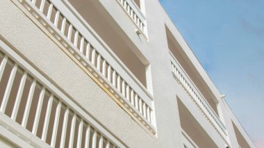 Günbatımında Panorama Puffy Bulutları La Jolla, California 'daki beyaz bir binanın alçak açılı görüntüsü. Açık gri metal parmaklıkları ve terası gökyüzünün arka planında olan bir binanın dışı..