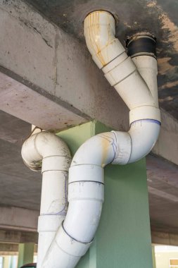 Destin, Florida. Aşağıdaki otoparktan beyaz PVC drenaj boruları görünüyor. Beton sütunların yanındaki boruları beton tavandan boşalt..