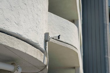 Destin, Florida 'da duvara monte edilmiş bir kamera görüntüsü. Güvenlik kamerası görüntüsü alçak açılı eğri bir binanın beyaz duvarına monte edilmiş..