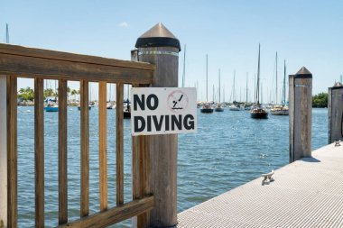 Miami Bay, Florida 'da marinada tahta parmaklıklarda dalış işareti yok. Açık gökyüzü arka planında yatların görüntüsü var.