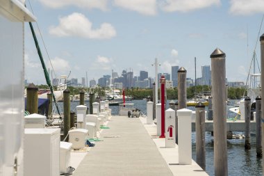 Marina, Miami, Florida 'daki körfezde kutularla kenetleniyor. Teknelerin yanında direkler ve gökyüzüne karşı modern binaların manzarası var..