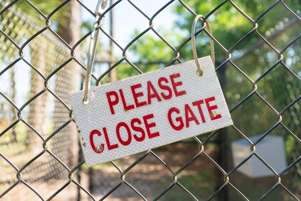 stock image Sign with Please Close Gate hanged with a rope on a chain link fence- Navarre, Florida. Tilted signboard outdoors on a metal chain link fence.