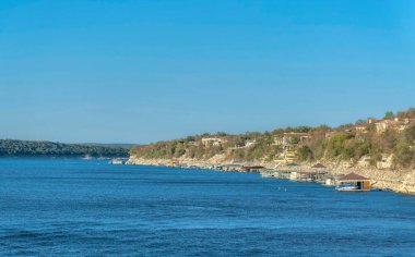Austin, Teksas. Austin Gölü kıyısı olan bir yamacın tepesinde zengin bir mahalle. Yamacın dibinde tekne rıhtımı ve temiz bir arka plan var..