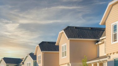 Panorama Fısıldayan Beyaz Bulutlar Vinil ahşap kaplamalı ve dangalak çatı yapısı olan evler. Güney Ürdün, Utah 'ta, Daybreak' teki meskûn evler gökyüzünün mavi arka planına karşı.