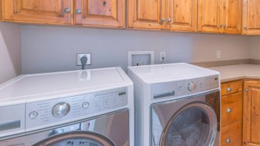 Panorama Çamaşırhanesi, zemin ve duvar ahşap dolaplarla dolu. Solda, duvardaki dolapların altındaki dolapların yanında iki tane ön yükleme ünitesi var..