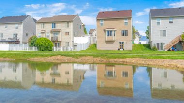 Panorama Fısıldayan Beyaz Bulutlar. Utah Vadisi halkı. Yansıtıcı göl kıyısına sahip. Önünde beton yolu olan çok katlı evler var..