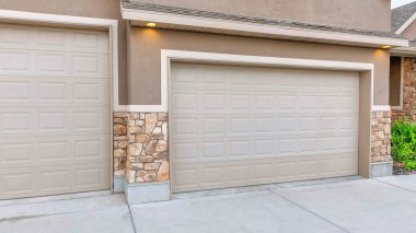 Açık kahverengi kaplamalı Panorama 3 arabalı garaj. Beton garaj yolu ve beton ve taş kaplamalı kaplamalı iki bölümlü garaj kapısı var..