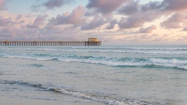 Günbatımında Panorama Kabarık Bulutları Kaliforniya 'daki Oceanside' da iskelesi ve kumlu sahili olan boş plajlar. Durgun okyanus dalgaları, beyaz günbatımı arka planında bir rıhtım manzaralı..