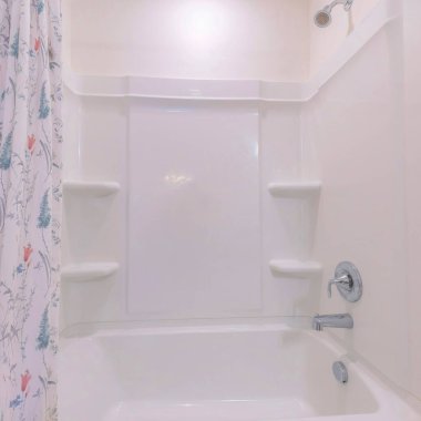 Akrilik duvar paneli ve banyo kombine seti. Duvara monte edilmiş paslanmaz duş başlığı ve solda musluk ve sağda basılı çiçek perdesi var..