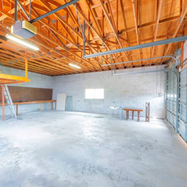 Otomatik kapı operatörü olan kare büyüklüğünde bir garaj. Ahşap iskeleti, penceresi ve boş blokları olan bitmemiş bir garajın içi..