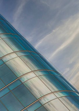 Günbatımında dikey kabarık bulutlar, Utah 'taki Salt Lake City' de bulutlu gökyüzüne karşı cam perde duvarlı dış bina. Solunda cam, sağında bulutlu bir gökyüzü olan bir binanın dışı..