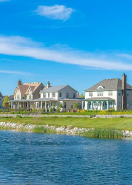 Dikey Whispy beyaz bulutları. Oquirrh Gölü 'nün mavi suyu. Kıyısında kayalar ve çimenler var. Utah, Daybreak 'teki büyük yerleşim yerlerinin ortasında göl..