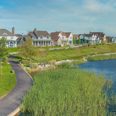 Utah 'ta Şafak vakti, Kare Fısıldayan Beyaz Bulutlar' ın yanında asfalt kaldırım var. Gölün üzerinde bir köprü ve arka planda dağlara karşı farklı yapılara sahip evler var..