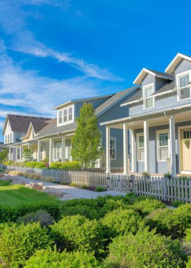 Utah, Daybreak 'teki bir konutta iki beton kaldırımın ortasında çalılarla çevrili dikey Whispy beyaz bulutları. Asfalt kiremitli ve sağ tarafında bahçe çitli verandalı geleneksel evler var..