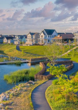 Gün batımında, Daybreak yerleşim yerindeki Oquirrh Gölü 'nde dikey kabarık bulutlar ve yanında beton kaldırımlar. Şafak 'ın yerleşim alanının yüksek açılı görüntüsü otlar ve çalılarla dolu bir tepeden..