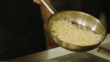 Profesyonel bir şef kızartma tavasında ustalıkla yemek hazırlar. Kızartma tavası ve elleri yakın çekim. Yüksek kaliteli FullHD görüntüler