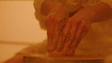 Çömlekçinin tekerinde kilden bir parça şekillendiren kadın çömlekçinin elleri. Yakın plan. Atış yavaşladı..