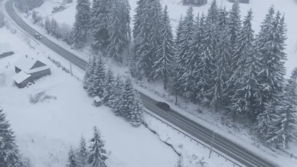 在暴风雪中 在冰雪覆盖的道路上驾驶汽车的无人驾驶飞机俯瞰着汽车的全景 — 图库视频影像
