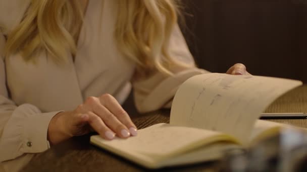 女性美丽的手在桌边翻动着纸本笔记本的书页 — 图库视频影像