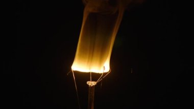 Camdan bir lambanın içindeki tungsten teli siyah arka planda yavaş çekimde camı kırdıktan sonra sigara içerek yakınlaşır..