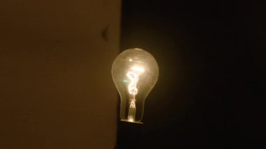 Tungsten ampul lambası siyah arka planda açılır ve kapanır. Eski antika ampulün yakın çekim görüntüsü ampulü güçlendirir. Rahatlık konsepti.