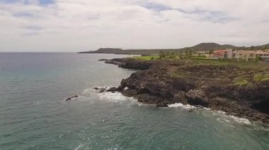 Kayalık bir sahil boyunca okyanus dalgaları. Yavaş çekim deniz manzarası, destansı kayalar ve dalgalar köye çarpıyor. Manzaranın sinematik drone görüntüsü