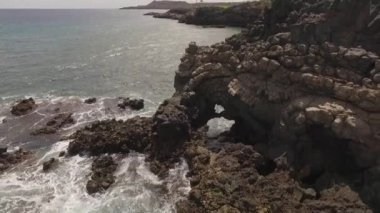 Kayalık bir sahil boyunca okyanus dalgaları. Yavaş çekim deniz manzarası, destansı kayalar ve dalgalar köye çarpıyor. Manzaranın sinematik drone görüntüsü