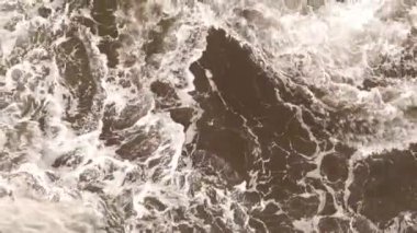 Kayalık bir sahil boyunca okyanus dalgaları. Yavaş çekim deniz manzarası, destansı kayalar ve dalgalar köye çarpıyor. Manzaranın sinematik drone görüntüsü