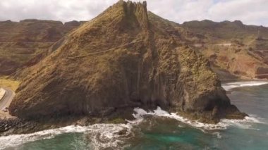 Kayalık bir sahil boyunca okyanus dalgaları. Yavaş çekim deniz manzarası, destansı kayalar ve dalgalar köye çarpıyor. Manzaranın sinematik drone görüntüsü