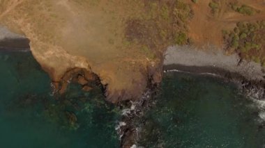 Mavi okyanusun yukarısından nefes kesici yavaş çekim görüntüsü ve kayalara çarpan dalgalar..