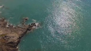 Mavi okyanusun yukarısından nefes kesici yavaş çekim görüntüsü ve kayalara çarpan dalgalar..