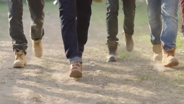 Πόδια Αρκετών Ανδρών Τζιν Και Καφέ Μπότες Που Περπατούν Χωματόδρομο — Αρχείο Βίντεο