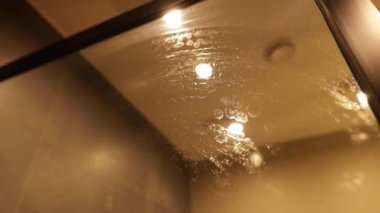 Banyodaki bardağı mikrofiber bezle temizleyen bir kadının yakın çekimi..