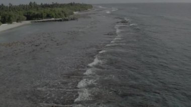 Deniz kıyısındaki sakin dalgaların üzerinde uçan bir dronun hava görüntüsü. Renk düzeltmesi olmadan HD video