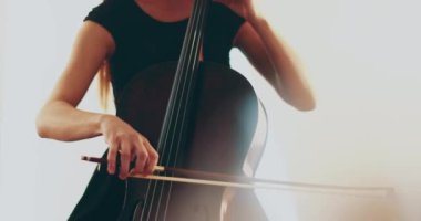Çello çalan bekar bir kadın, yakın çekim ve orta boy, çello yayı ve teller, kameranın odak noktasından odak dışına geçişi, güzel film, sanatsal çekimler.