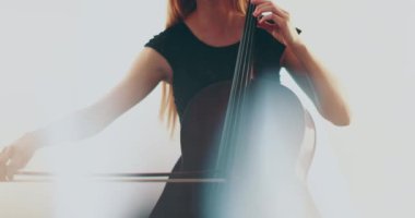 Çello çalan bekar bir kadın, yakın çekim ve orta boy, çello yayı ve teller, kameranın odak noktasından odak dışına geçişi, güzel film, sanatsal çekimler.