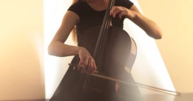 Çello çalan bekar bir kadın, yakın çekim ve orta boy, çello yayı ve teller, kameranın odak noktasından odak dışına geçişi, güzel film, sanatsal çekimler.