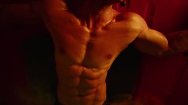 Yakından bakınca güçlü yakışıklı bir adamın portresi. Çok renkli ışıkta poz veren sağlıklı spor fitness modeli. Çıplak vücutlu seksi moda adamı. Yüzü olmayan