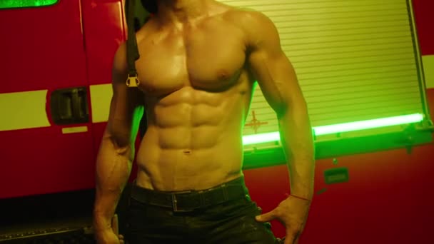 消防士は裸の胴を持つ消防車の隣にハンマーを手に立っている フィットネスモデルの消防士 ハンサムな男 モデル — ストック動画